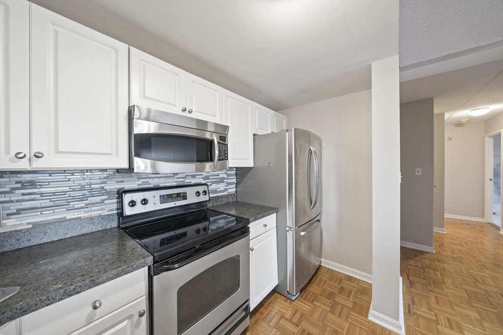 155 George Washington Boulevard, Unit 402 Hull, MA 02045 - Photo 5 of 42 a kitchen with granite countertop a refrigerator and a stove
