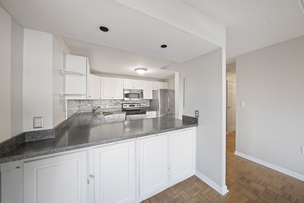 155 George Washington Boulevard, Unit 402 Hull, MA 02045 - Photo 7 of 42 a kitchen with stainless steel appliances granite countertop a sink a refrigerator and white cabinets