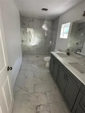 a bathroom with a granite countertop sink a toilet and shower