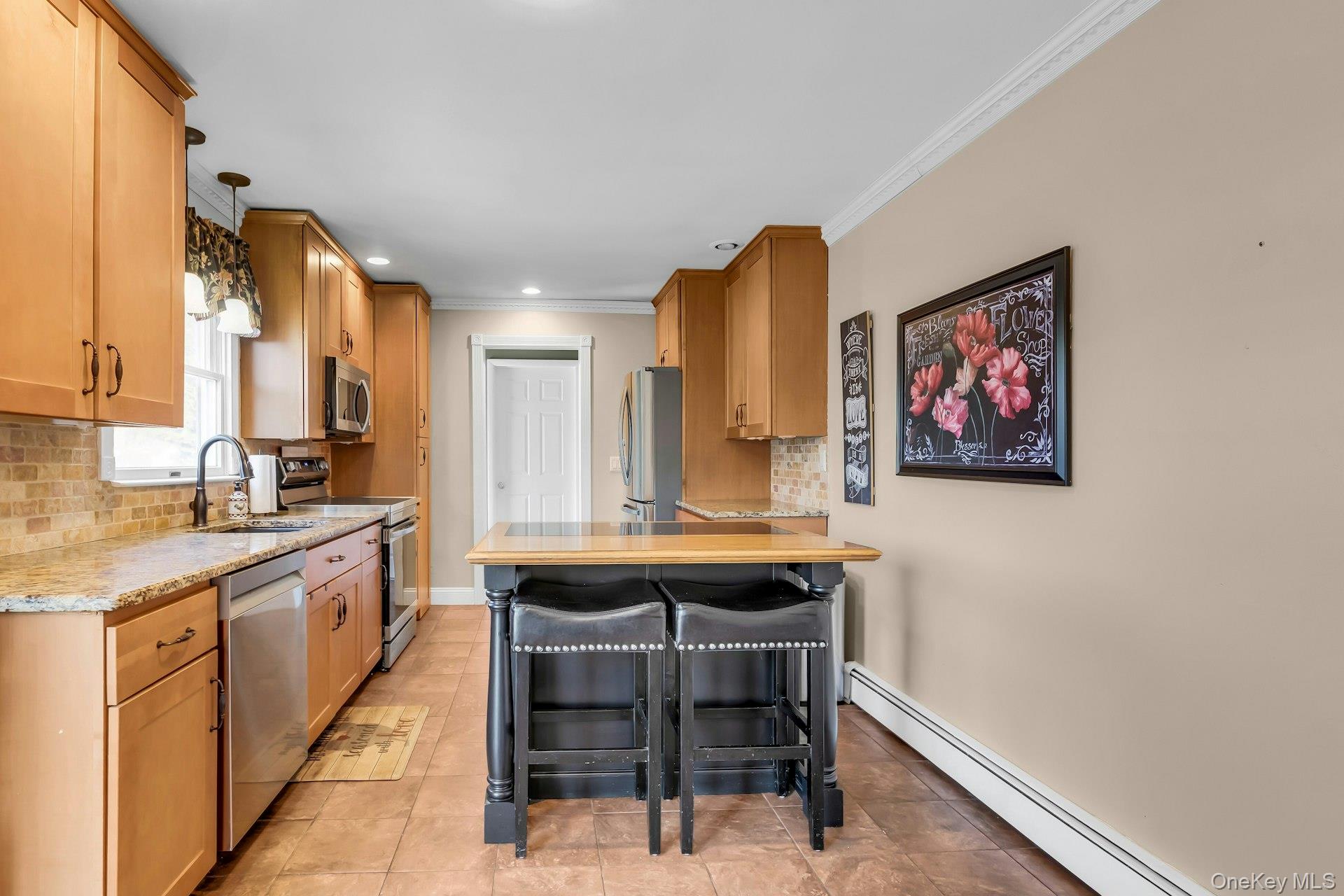 358 Rider Avenue Patchogue, NY 11772 - Photo 12 of 25 Kitchen featuring decorative backsplash, a kitchen bar, a baseboard heating unit, a peninsula, and crown molding