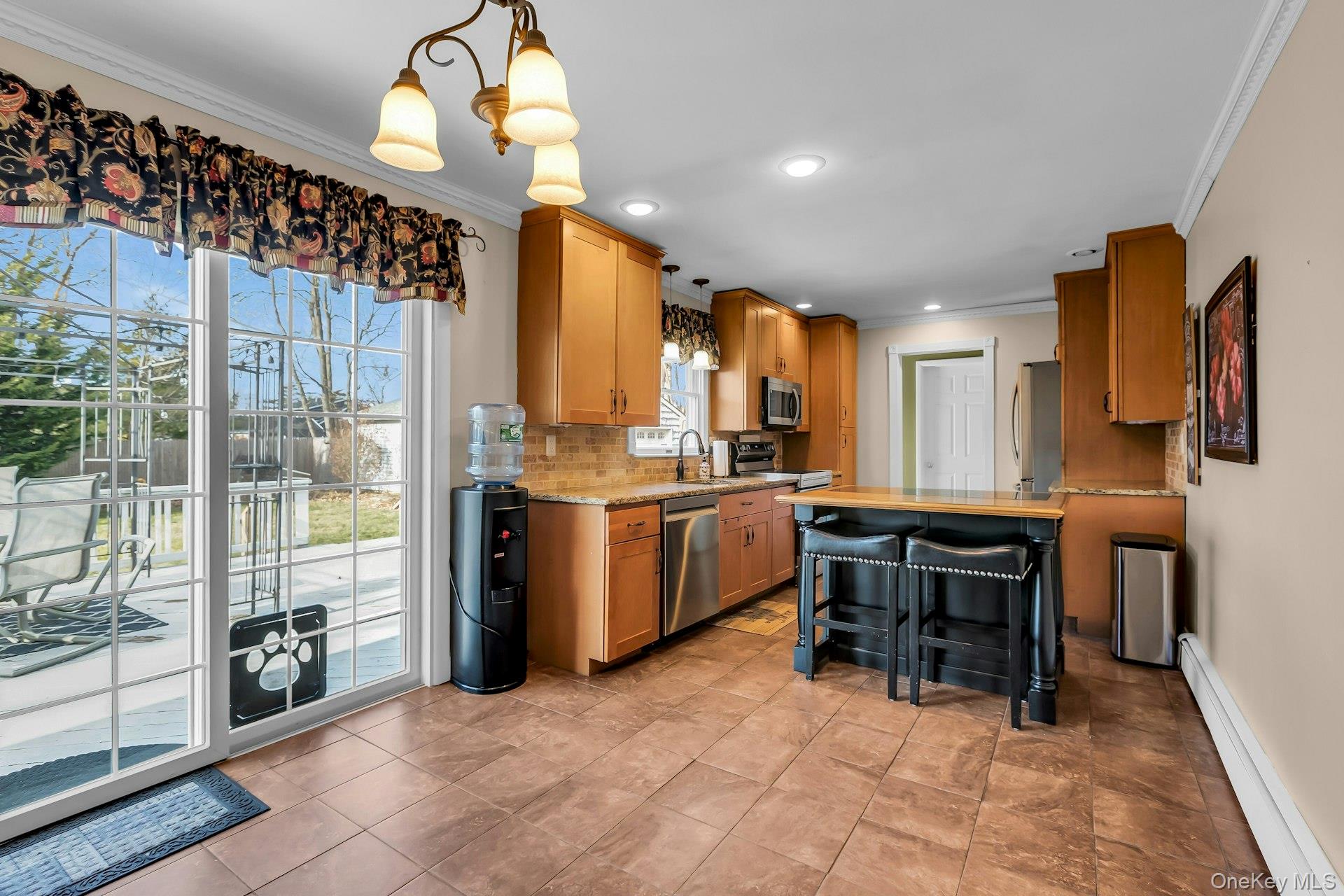 358 Rider Avenue Patchogue, NY 11772 - Photo 14 of 25 Kitchen with a baseboard radiator, pendant lighting, ornamental molding, a kitchen breakfast bar, and tasteful backsplash
