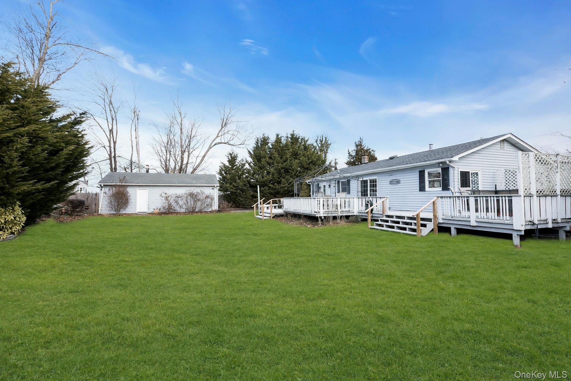 358 Rider Avenue Patchogue, NY 11772 - Photo 25 of 25 Rear view of property with a lawn, a deck, an outbuilding, and a shingled roof