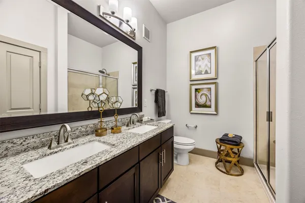 a bathroom with a granite countertop double vanity sink and mirror