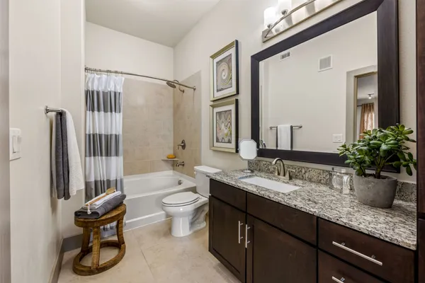 a bathroom with a granite countertop sink a toilet and shower