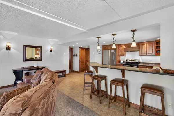 a kitchen with stainless steel appliances granite countertop a refrigerator a stove a sink a dining table and chairs with wooden floor