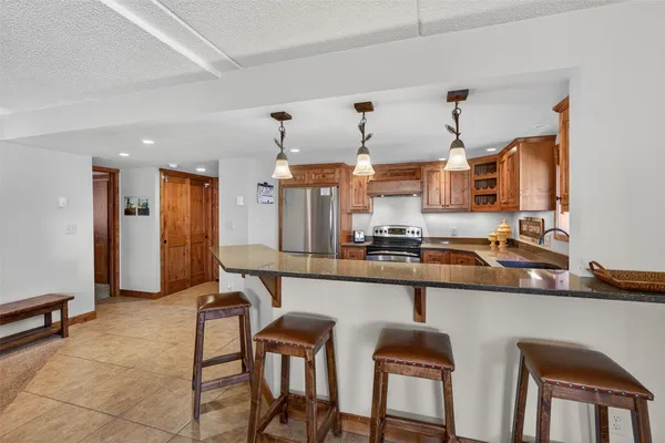 a kitchen with stainless steel appliances granite countertop a refrigerator a stove a sink a dining table and chairs