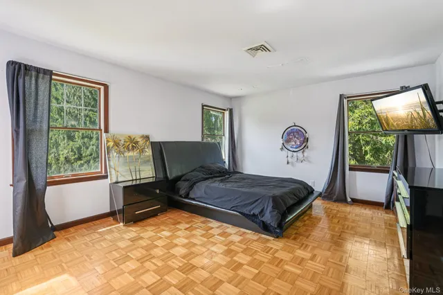 a spacious bedroom with a bed and a dresser next to a window