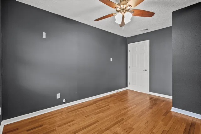 an empty room with a ceiling fan and wooden floor