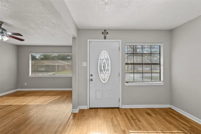 an empty room with wooden floor cabinet and windows