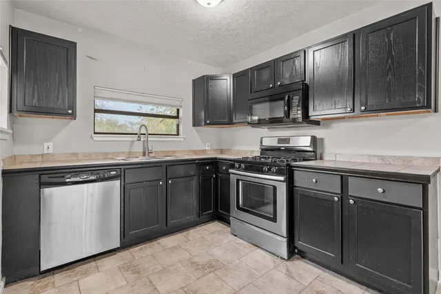 a kitchen with stainless steel appliances granite countertop wooden cabinets a stove top oven a sink and dishwasher