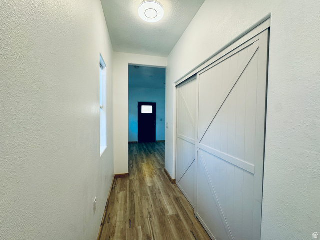 150 North 3050 East, Unit 4 St. George, UT 84790 - Photo 15 of 24 Hallway featuring wood-finish flooring, a flush-mount ceiling light, a window, and white sliding barn-style doors