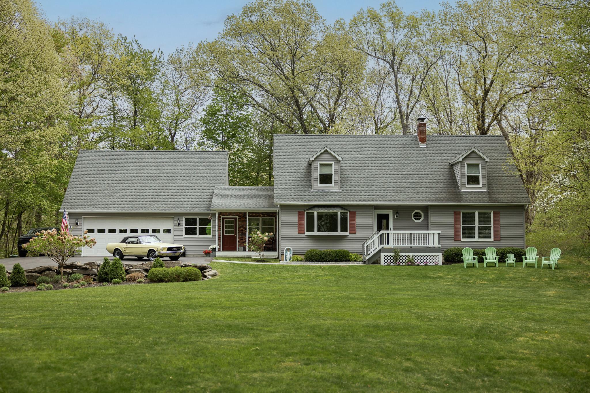 a front view of a house with a garden and trees