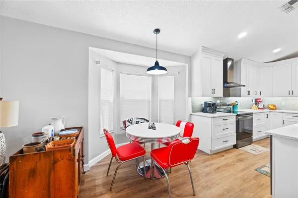 a kitchen with stainless steel appliances kitchen island granite countertop a dining table chairs and white cabinets