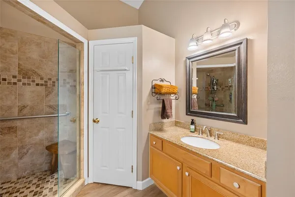 a bathroom with a granite countertop sink a mirror and a shower