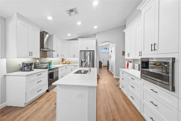 a large white kitchen with stainless steel appliances and white cabinets