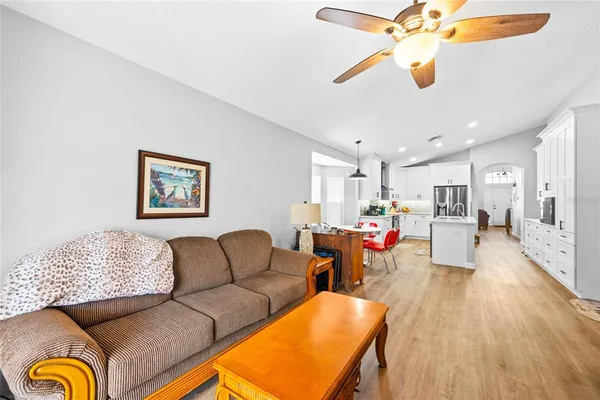 a living room with furniture kitchen view and a chandelier