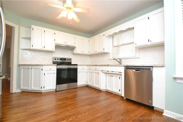 a kitchen with granite countertop white cabinets and white appliances