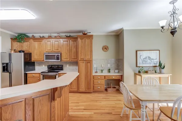 a kitchen with stainless steel appliances a stove top oven a refrigerator a dining table and chairs