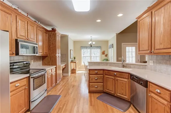 a kitchen with stainless steel appliances granite countertop a stove top oven a sink dishwasher and cabinets with wooden floor