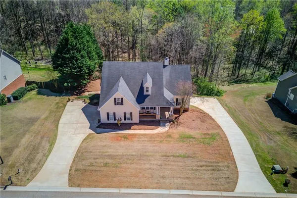 an aerial view of a house with swimming pool and large trees