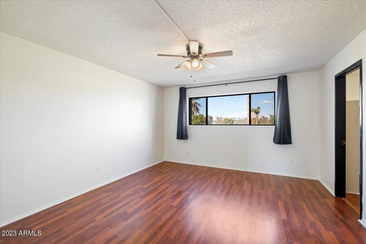 2524 South El Paradiso, Unit 50 Mesa, AZ 85202 - Photo 13 of 36 an empty room with wooden floor ceiling fan and windows