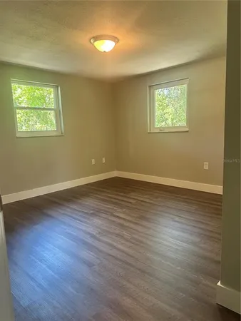 a white house with a big yard plants and large trees