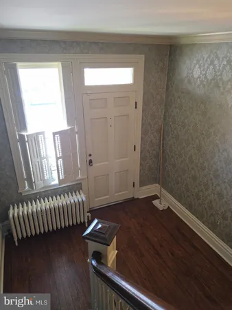 an empty room with wooden floor fireplace and windows