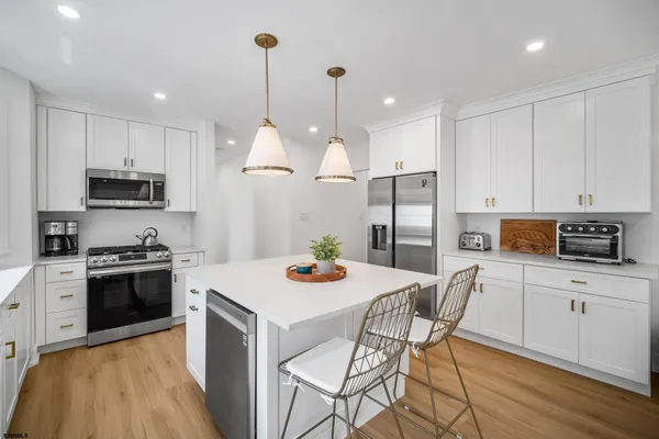 a kitchen with stainless steel appliances kitchen island granite countertop a sink a stove a dining table and chairs