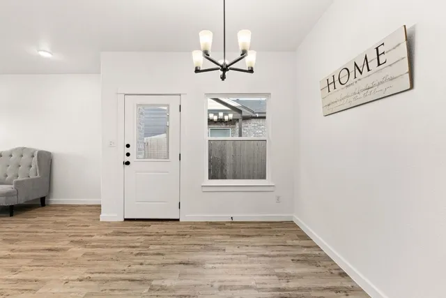 a view of an empty room with window and wooden floor