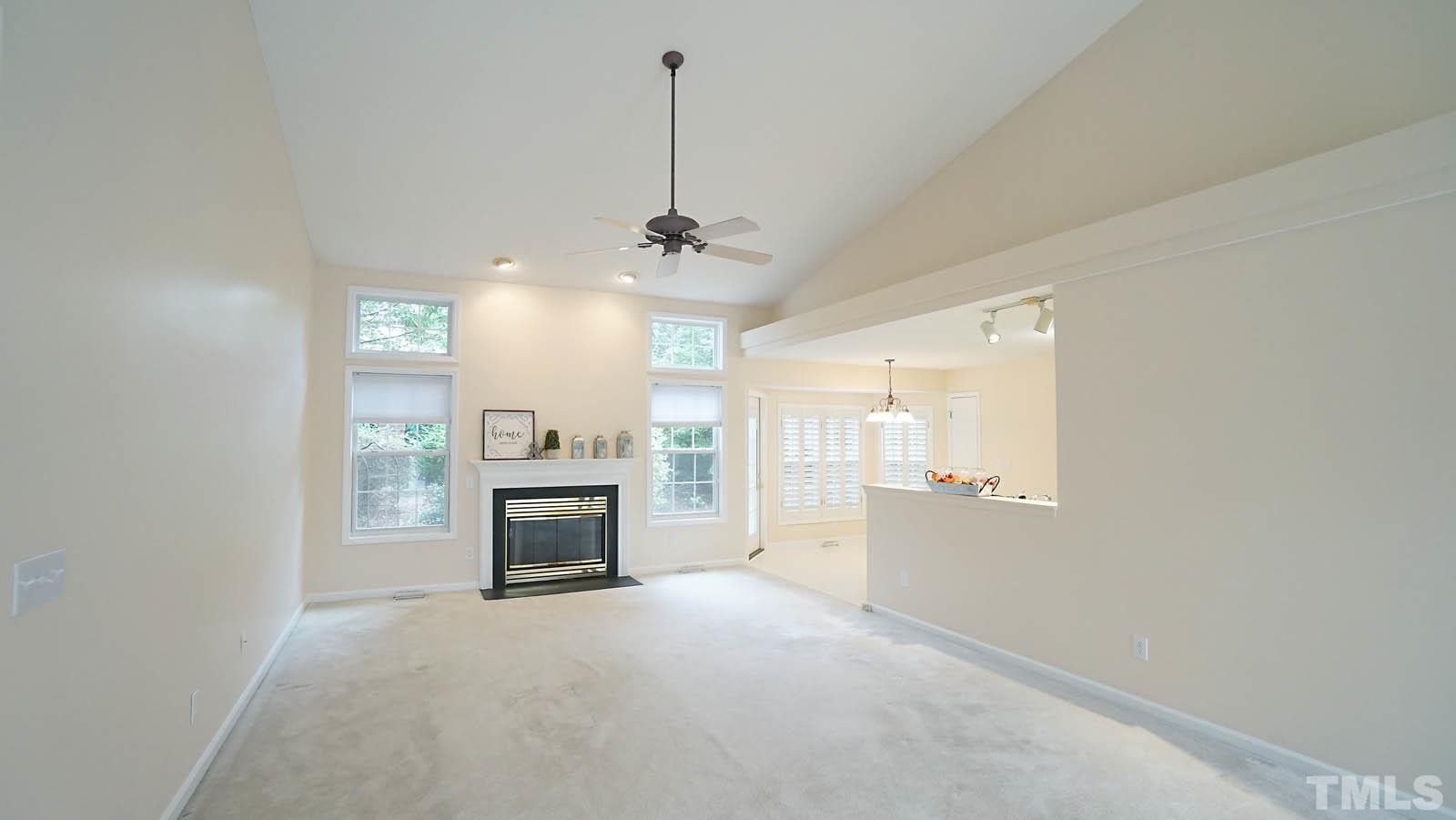 8316 Trumpetor Way Raleigh, NC 27613 - Photo 6 of 26 a view of a livingroom with a fireplace a chandelier a wooden table and chairs