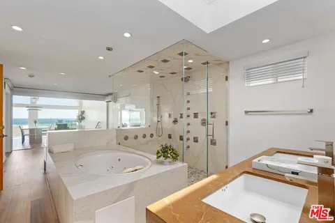 a bathroom with a tub a sink and a large mirror