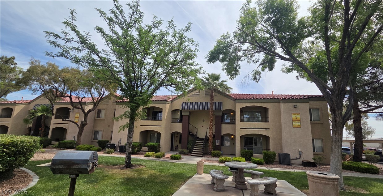 7885 West Flamingo Road, Unit 1008 Las Vegas, NV 89147 - Photo 25 of 29 A terracotta-roofed apartment complex nestled amidst mature trees and verdant landscaping beckons with inviting balconies and communal gathering spots.