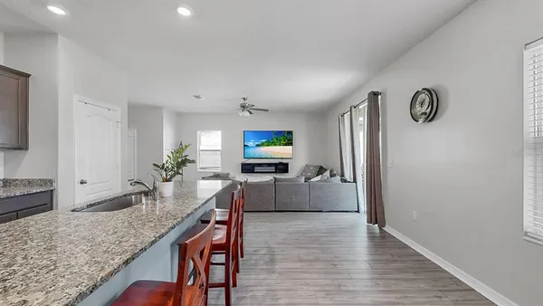 a living room with kitchen island granite countertop furniture and a wooden floor