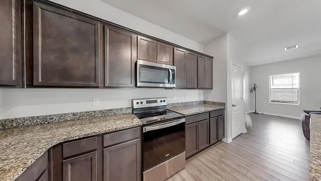 a kitchen with stainless steel appliances granite countertop a stove a sink and a microwave