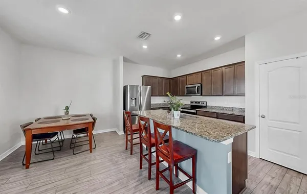 a kitchen with stainless steel appliances granite countertop a table chairs sink and cabinets