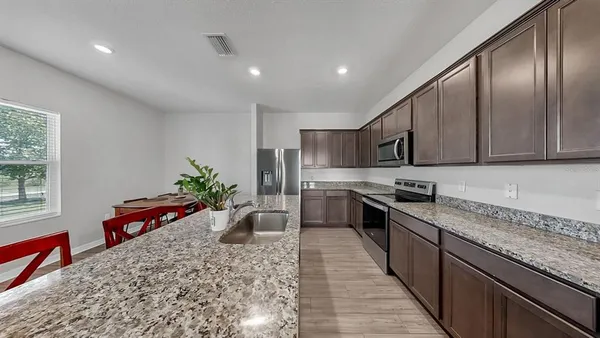 a kitchen with stainless steel appliances granite countertop sink stove top oven and cabinets