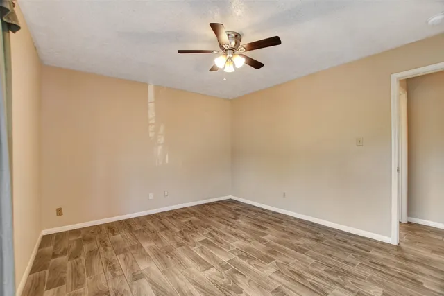 an empty room with wooden floor and ceiling fan