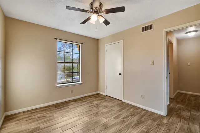 a view of empty room with wooden floor and fan