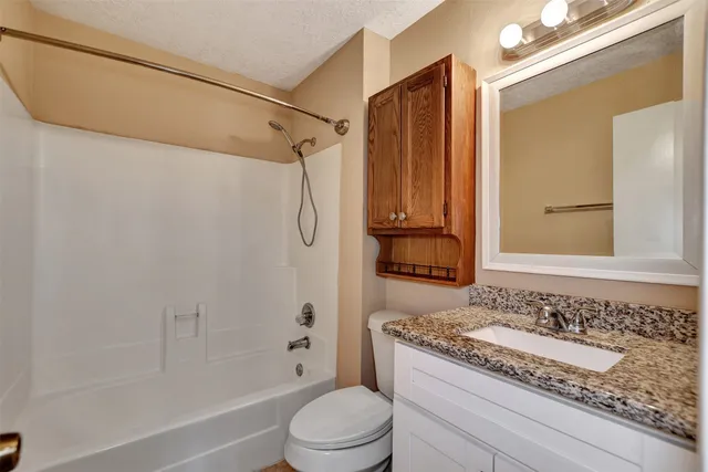 a bathroom with a granite countertop sink toilet and shower