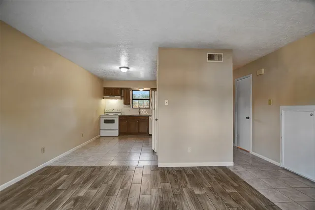 a view of a kitchen and an empty room with wooden floor and a kitchen