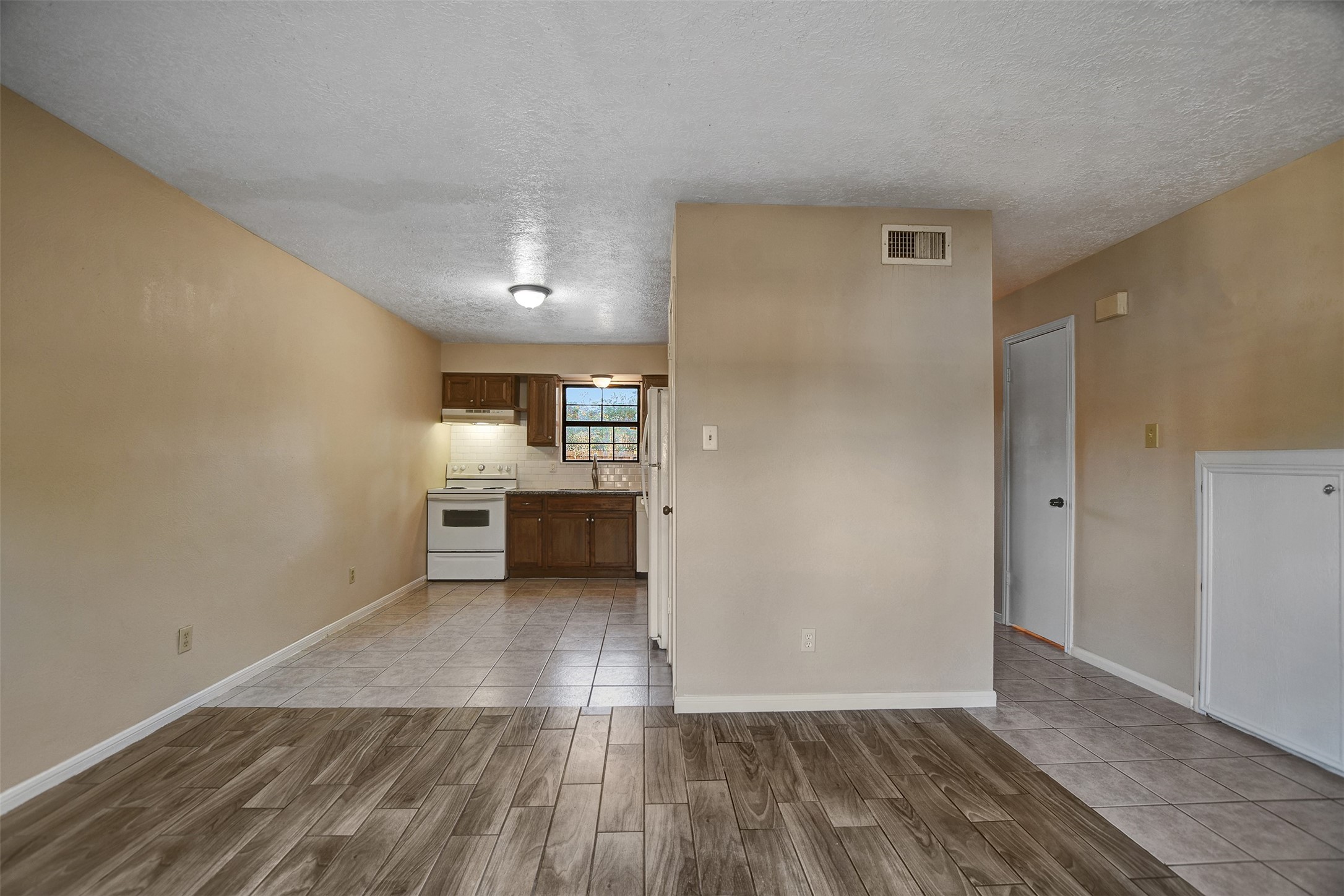 1706 Longview Street, Unit 1 Conroe, TX 77301 - Photo 7 of 32 a view of a kitchen and an empty room with wooden floor and a kitchen