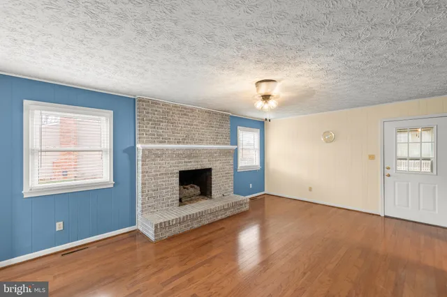 an empty room with windows and fireplace
