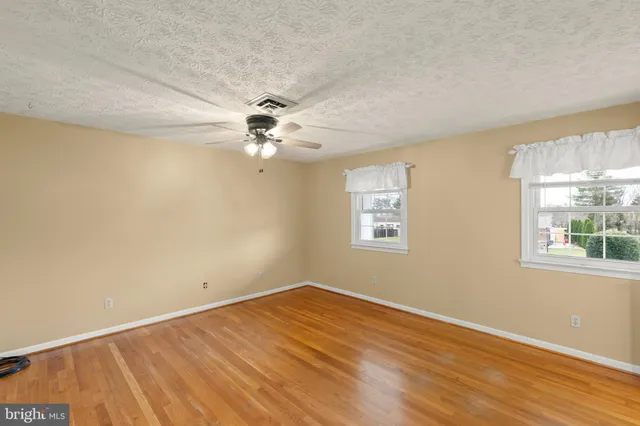 a view of a room with wooden floor and a ceiling fan