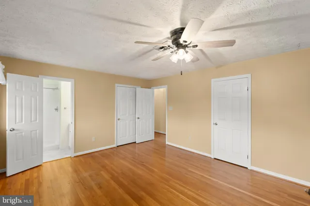 a view of empty room with wooden floor and fan