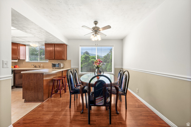 1650 Nichole Circle Sandy, UT 84093 - Photo 5 of 31 Dining area featuring wood-finish flooring, a ceiling fan with light fixture, and a window with blinds overlooking greenery