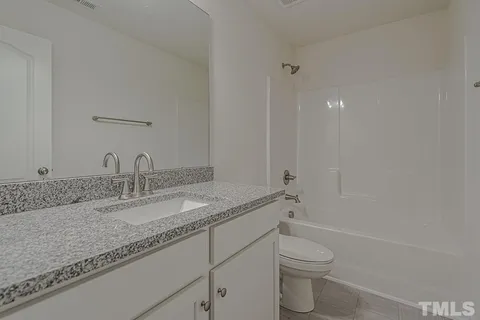 a bathroom with a granite countertop sink a toilet and a mirror