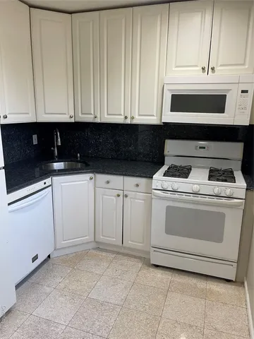 a kitchen with white cabinets and white appliances