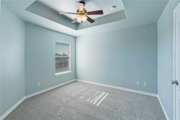 an empty room with a ceiling fan and windows