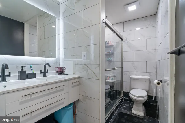 a bathroom with a granite countertop sink a toilet and a shower