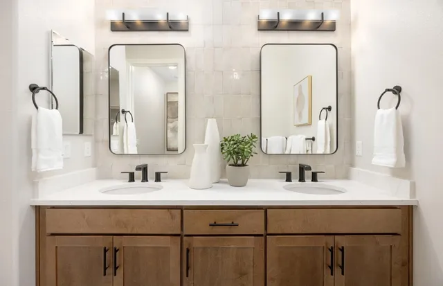 a bathroom with double vanity sinks and two mirror